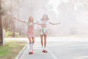 full length view of two girls skateboarding in smoke on road