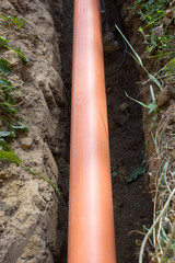 sewer pipe in a pit,PVC pipe is laid in the trench for sewage system, orange sewer pipe