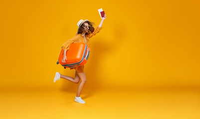 concept of travel. happy woman girl with suitcase and  passport on  yellow background.