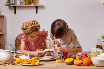 Little friends are making a cake together at a kitchen against a white wall with shelves on it.