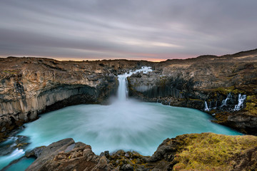 Aldeyjarfoss waterfall in Iceland at sunrise with golden clouds in the sky. Amazing landscape in beautiful tourist attraction. Wonder of nature with glacier water.