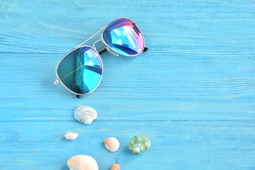 Trendy aviator sunglasses and colorful tropical seashells with selective focus on textured wood...