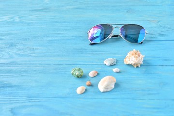 Trendy aviator sunglasses and colorful tropical seashells with selective focus on textured wood...