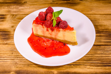 White plate with cheesecake New York, leaf of mint and raspberries on wooden table