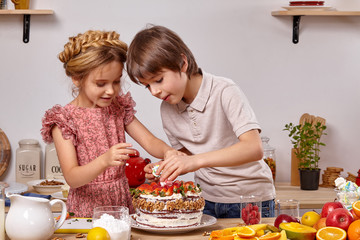 Little friends are making a cake together at a kitchen against a white wall with shelves on it.