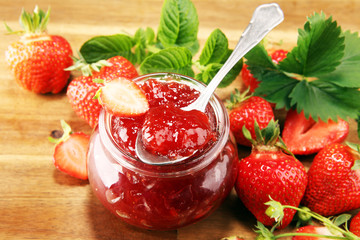 strawberry jam with fresh strawberries and mint. marmalade on spoon and jar on brown wood