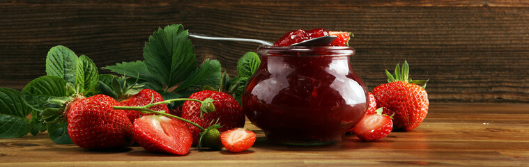 strawberry jam with fresh strawberries and mint. marmalade on spoon and jar on brown wood