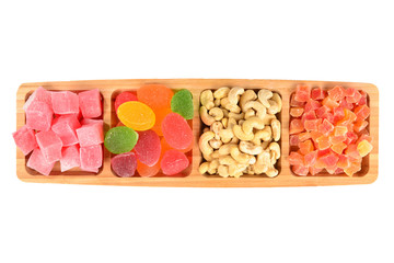 Wooden plate with cashew, marmalade and sweet turkish delight. Isolated on white background. Space for text or design.