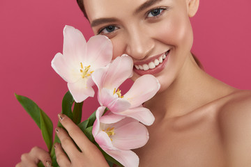 Joyful pretty girl with naked shoulders holding beautiful tulips