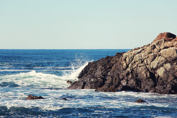 sea waves on rocks over blue sky