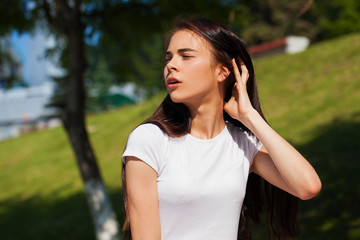 Beautiful brunette woman posing against summer park, bright sunny weather