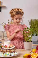 Little girl is making a homemade cake with an easy recipe at kitchen against a white wall with shelves on it.