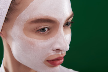 Beautiful young woman using facial cleansing mask