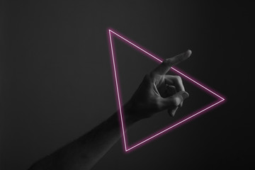 Hand pointing a finger against a dark background with abstract neon light glow