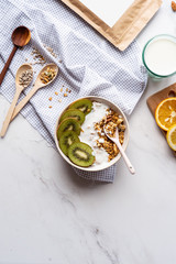 Healthy breakfast bowl with spoon concept, detox morning meal on table background, vegan natural fruit nut granola fitness nutrition with kiwi yoghurt, detox organic food concept, vertical top view