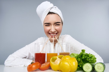 Smiling woman enjoying juices after spa isolated on grey background