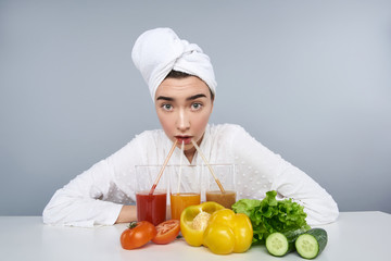 Surprised girl sipping organic drinks against grey background