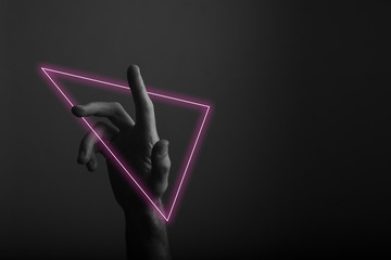 Hand pointing a finger against a dark background with abstract neon light glow