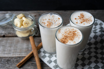 Banana smothie or milkshake with cinnamon on wood background