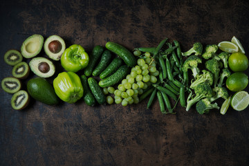 Healthy green food. Clean food. Pure choice and source of vegetable protein on wooden aged background. Avocado, grapes, cucumbers, kiwi, apples, broccoli, lime, green peas, green pepper.