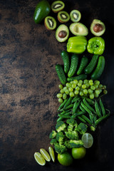 Healthy green food. Clean food. Pure choice and source of vegetable protein on wooden aged background. Avocado, grapes, cucumbers, kiwi, apples, broccoli, lime, green peas, green pepper.