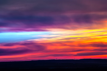 The fiery sky above the silhouette of the horizon of the Russian steppe, bright colorful clouds of red yellow color hide the setting sun. Sunset over Ufa, Bashkortostan, Russia.