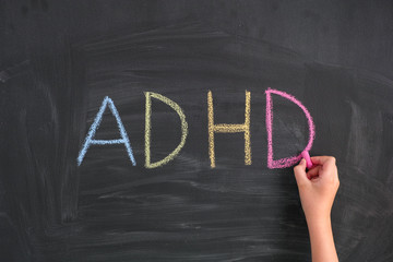 Child writing Abbreviation ADHD on a blackboard - obrazy, fototapety, plakaty