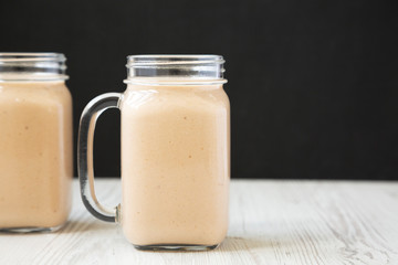 Healthy banana apple smoothie in glass jars, side view. Copy space.