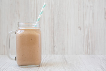 Banana apple smoothie in a glass jar mug, side view. Space for text.