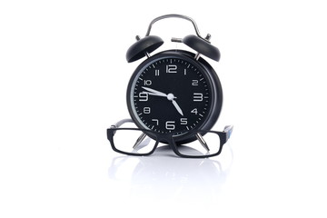 alarm clock with glasses on white background