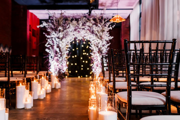 Wedding ceremony decorations in loft grunge surround. Light bulb garland, candles, glass, chairs and candlesticks. Ceremony in purple color. Exit registration inside.