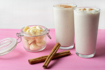 Banana smothie or milkshake with cinnamon on pink  background