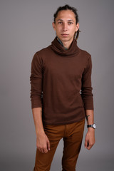 Fototapeta premium Young man with dreadlocks wearing brown shirt against gray backg