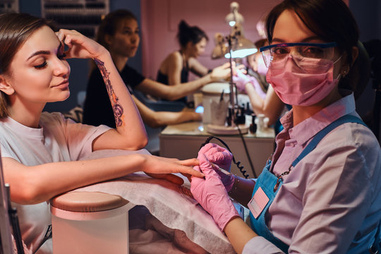 Beautiful smiling woman has nice time at beauty salon while getting new trendy manicure.