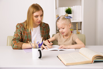 Girl with mother studying together at the desk at home