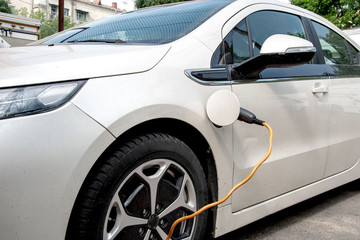 Obraz na płótnie Canvas The electric car is charged from the mains, the cable from the charging station
