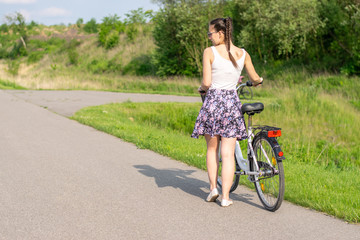 Naklejka premium Active life. A woman with a bike enjoys the view at summer forest. Bicycle and ecology lifestyle concept.