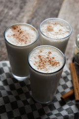 Banana smothie or milkshake with cinnamon on wood background