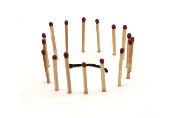 matches stand in the circle around a burnt match on a white background