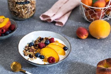 Granola with yogurt fresh peach, blueberry, raspberry on the table - healthy breakfast