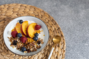 Granola with yogurt fresh peach, blueberry, raspberry on the table - healthy breakfast