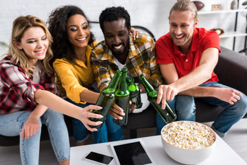 selective focus of happy multicultural friends toasting in living room