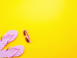 Summer flat lay. Beach accessories pink flip flops and sunglasses on yellow background. Summer trevel and vacation concept