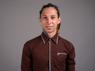 Fototapeta premium Young man with dreadlocks wearing brown shirt against gray backg