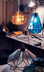 Master's workspace, table and beautiful colourful glass lamps at cozy workshop.