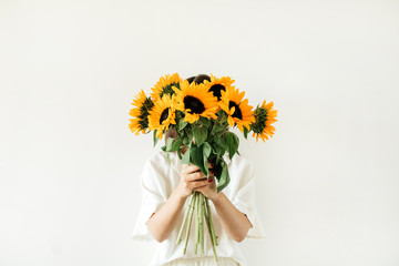 Young pretty woman in white dress hold sunflowers bouquet on white background. Florist minimal...