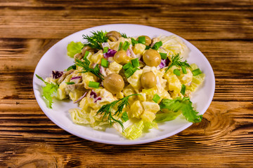 Salad with marinated mushrooms, eggs, red onion, boiled potato and mayonnaise on wooden table