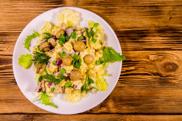 Salad with marinated mushrooms, eggs, red onion, boiled potato and mayonnaise on wooden table. Top view