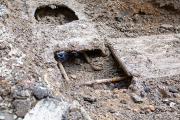 Old rusted water pipes in a concrete gutter.