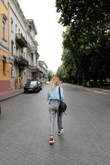 a beautiful girl walks through the streets of a European city, she is a student in her hands a notebook a